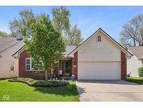 Charming brick home featuring a two-car garage, landscaped front yard, and a well-maintained lawn at 7450 Deville Ct, Indianapolis, IN 46256