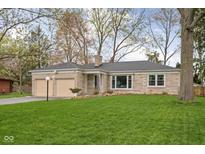 Charming stone home featuring an attached two-car garage and a well-maintained lawn at 928 Forest Blvd N Dr, Indianapolis, IN 46240