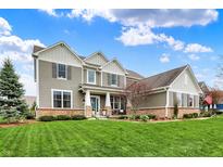 Inviting two-story home with a well-manicured lawn, neutral siding, brick accents, and a charming teal-colored front door at 10235 Normandy Way, Fishers, IN 46040
