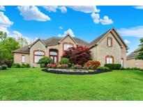 Stunning stone home with lush landscaping, mature trees, and a well-manicured lawn at 13758 Foxdale Lake Dr, Carmel, IN 46032