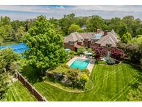 Expansive backyard with pool, tennis court, and lush landscaping surrounds this elegant brick home at 290 Breakwater Dr, Fishers, IN 46037