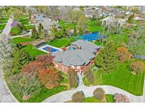 Aerial shot of a beautiful brick home with a pool and tennis court amidst lush greenery at 290 Breakwater Dr, Fishers, IN 46037