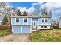 Split-level home boasts a colorful facade, attached two-car garage, and a welcoming entryway at 11423 Mutz Cir, Indianapolis, IN 46229