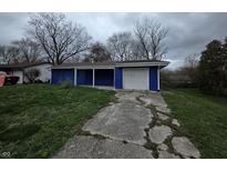 Cozy one-story home featuring blue siding, an attached garage, and a cracked driveway at 3162 Wallace Ave, Indianapolis, IN 46218