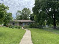 Charming single-story home featuring a lush lawn, mature trees, and a welcoming walkway at 3315 Hillcrest Dr, Columbus, IN 47203