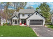 Charming two-story home with a landscaped front yard and an attached two-car garage, painted in white with black accents at 333 S Fourth St, Zionsville, IN 46077