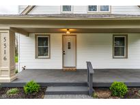 Inviting front entrance featuring a white door, decorative light fixture, and charming landscaping at 5516 S Randolph St, Indianapolis, IN 46227