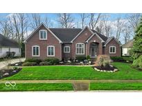 Charming brick home featuring manicured lawn and a well-designed garden bed at the front entrance at 5861 Dawnwood Dr, Carmel, IN 46033
