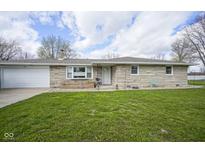 Charming stone facade ranch home with an attached garage and a well-manicured lawn at 712 Valley Dr, Anderson, IN 46011