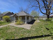 Charming home with a cozy front porch, surrounded by a lawn with some small yellow flowers at 716 Lynn St, Indianapolis, IN 46222