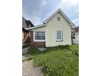 The home's facade features aged siding, a large window, and a small yard with scattered dandelions at 2157 S Meridian St, Indianapolis, IN 46225
