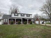 Charming two-story home with brick and white siding, a covered front porch, and well-maintained landscaping at 216 Golf Club Rd, Anderson, IN 46011