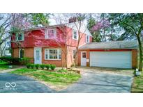 Charming two-story brick home featuring an attached garage and a well-maintained front yard with mature trees at 2215 W State Rd, Pendleton, IN 46064