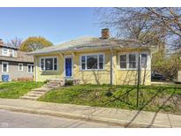 Charming yellow home with a blue front door, a landscaped lawn, and concrete steps leading to the entrance at 548 E 39Th St, Indianapolis, IN 46205