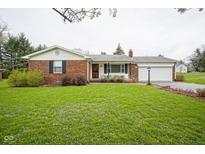 Charming brick home featuring an attached garage and a well-maintained lawn at 5555 W Vermont St, Indianapolis, IN 46224