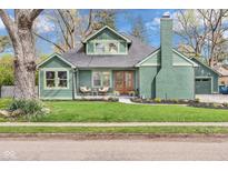 Charming green exterior view featuring well-kept lawn, inviting porch, and a view of the brick chimney and roof at 6185 Evanston Ave, Indianapolis, IN 46220
