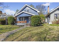 Charming blue two-story home with a cozy front porch, landscaped yard and brick accents, located in a neighborhood setting at 914 N Bancroft St, Indianapolis, IN 46201
