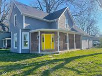 Charming two-story home with a welcoming porch, and a bright yellow front door at 1001 N 14Th St, Elwood, IN 46036