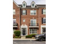 Charming brick townhouse featuring black shutters, dormer windows, and a well-maintained front garden at 1057 3Rd Nw Ave, Carmel, IN 46032