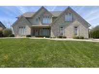 Traditional brick home with a lush green lawn and manicured landscaping in a suburban neighborhood at 1394 Cherry Tree Rd, Avon, IN 46123