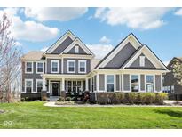 Inviting two-story home with a covered front porch, manicured lawn and beautiful architectural details at 14413 Arnett Dr, Carmel, IN 46033
