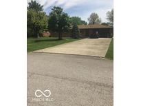 Spacious driveway leading to a single-story brick home with mature trees and a well-maintained lawn at 4329 Dudley N Dr, Indianapolis, IN 46237