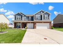 Charming two-story home featuring blue siding, brick accents, a well-manicured lawn, and a spacious two-car garage at 4638 W Otway Ln, New Palestine, IN 46163