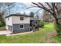 Two-story home showcasing gray brick and vinyl siding, accented by a spacious driveway and mature trees at 5302 E 46Th St, Indianapolis, IN 46226