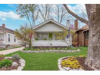 Charming home featuring a beautifully landscaped front yard with a stone-lined flower bed and vibrant tulip blooms at 5942 Primrose Ave, Indianapolis, IN 46220