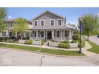 Charming two-story home boasts a welcoming front porch and a well-manicured lawn with a classic white picket fence at 7638 Beekman Ter, Zionsville, IN 46077