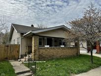Charming single-story home with a brick porch and a well-maintained front yard, complemented by a mature tree at 1020 N Colorado Ave, Indianapolis, IN 46201