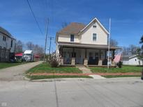 Charming two-story home featuring a cozy front porch and well-maintained front yard at 210 E Monroe St, Alexandria, IN 46001