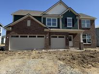 New two-story home featuring a brick facade, two-car garage, and complementary green and white siding accents at 5311 Pelion Pl, McCordsville, IN 46055