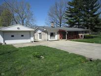 Quaint home featuring a front porch, chimney, detached garage, and well-maintained lawn at 7402 Alice Ave, Indianapolis, IN 46219
