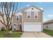 Inviting home with a two-car garage, neat landscaping and light brown siding at 10881 August Dr, Ingalls, IN 46048