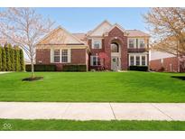Charming red brick two-story home with a well-manicured lawn and beautiful landscaping at 13933 Wildcat Dr, Carmel, IN 46033