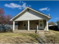 Charming home with a stone front, covered porch, and manicured lawn on a sunny day at 1517 N Gladstone Ave, Indianapolis, IN 46201