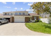 Charming brick townhouse featuring an attached garage, well-manicured lawn, and inviting curb appeal at 1520 Norfolk Dr, Zionsville, IN 46077