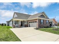 Charming brick and gray home with a well-manicured lawn and spacious driveway under a partly cloudy sky at 15781 Harvester E Cir, Noblesville, IN 46060