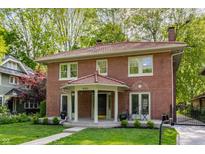 Beautiful two-story brick home featuring a unique red tile roof, inviting front porch, and lovely yard at 4343 N Pennsylvania St, Indianapolis, IN 46205