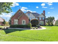 Charming brick and tudor home with manicured front lawn and mature trees under a blue sky at 4843 Snowberry Bay Ct, Carmel, IN 46033