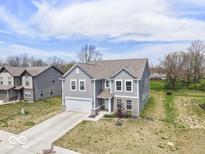 Two-story home with gray siding, a two-car garage, concrete driveway, and manicured lawn at 10524 Broadford St, Indianapolis, IN 46239
