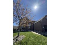 Two-story brick home with a manicured lawn, walkway, attached garage, and blossoming tree under a sunny sky at 1121 Retford Ct, Greenwood, IN 46143