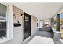 Charming front porch with gray siding, black door, and mailbox, perfect for enjoying the outdoors at 2114 N Dexter St, Indianapolis, IN 46202