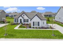 Stunning single-Gathering home with a white brick exterior, dark shutters, a gray roof and a perfectly manicured front lawn at 3840 Shady Lake Dr, Westfield, IN 46074