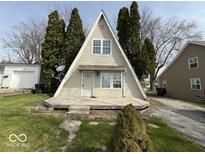 A-frame home featuring a unique design with a wooden porch, complemented by surrounding trees and well-kept lawn at 406 W Broadway St, Alexandria, IN 46001
