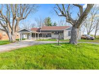 Charming single-story home features a covered carport, stone accents, and a lush green lawn at 7008 E Jackson St, Muncie, IN 47303