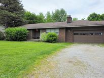 Charming brick home with a well-maintained lawn, mature trees, and a one-car attached garage at 935 Fry Rd, Greenwood, IN 46142