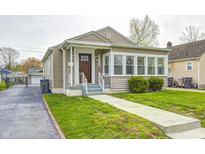 Charming bungalow with tan siding, a manicured lawn, and inviting front porch at 2009 N Bosart Ave, Indianapolis, IN 46218