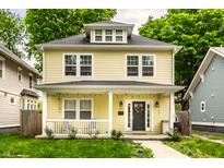Charming two-story yellow home featuring a welcoming front porch and well-manicured lawn at 3133 Ruckle St, Indianapolis, IN 46205